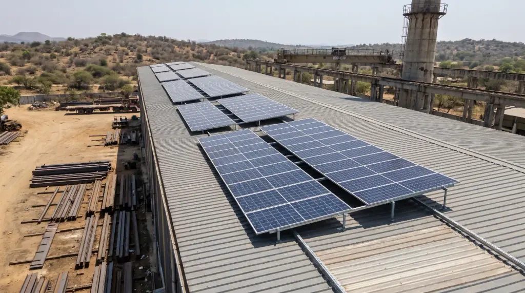 Rooftop solar array on a heavy engineering workshop with an overhead crane rail and chimney stack