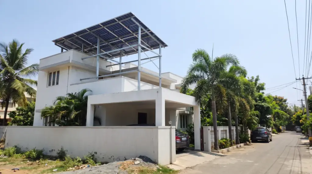 Rooftop solar system on an elevated structure over a modern white villa in Madipakkam