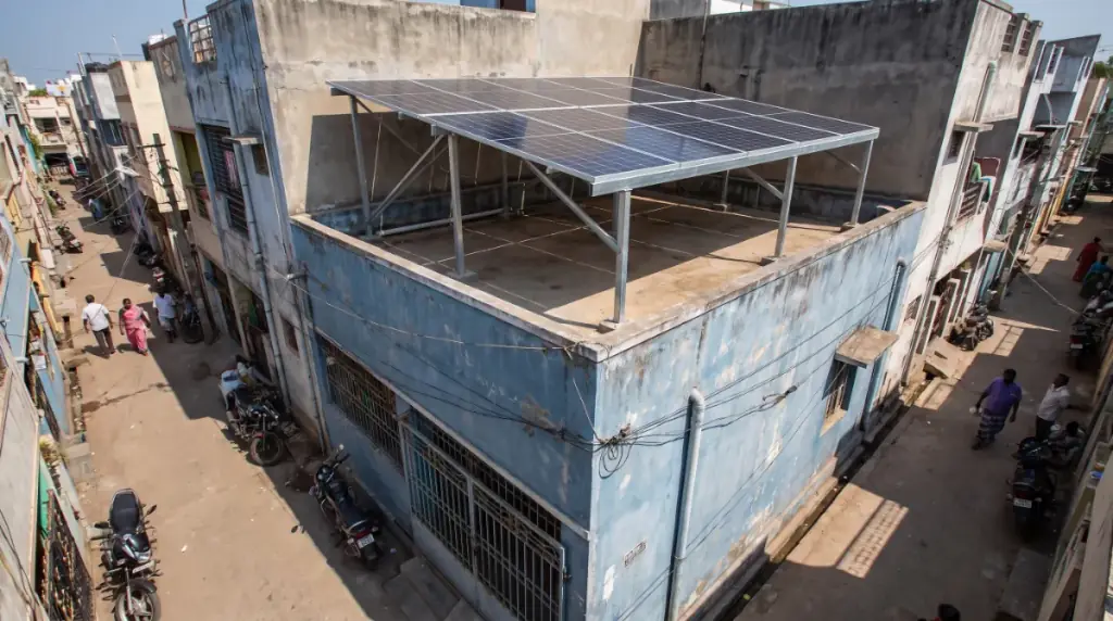 Rooftop solar system on an elevated structure over a narrow three-storey row house on a tight residential street in Pammal