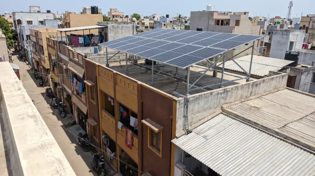 Rooftop solar system on an elevated structure over a narrow three-storey row house on a tight residential street in Thoothukudi