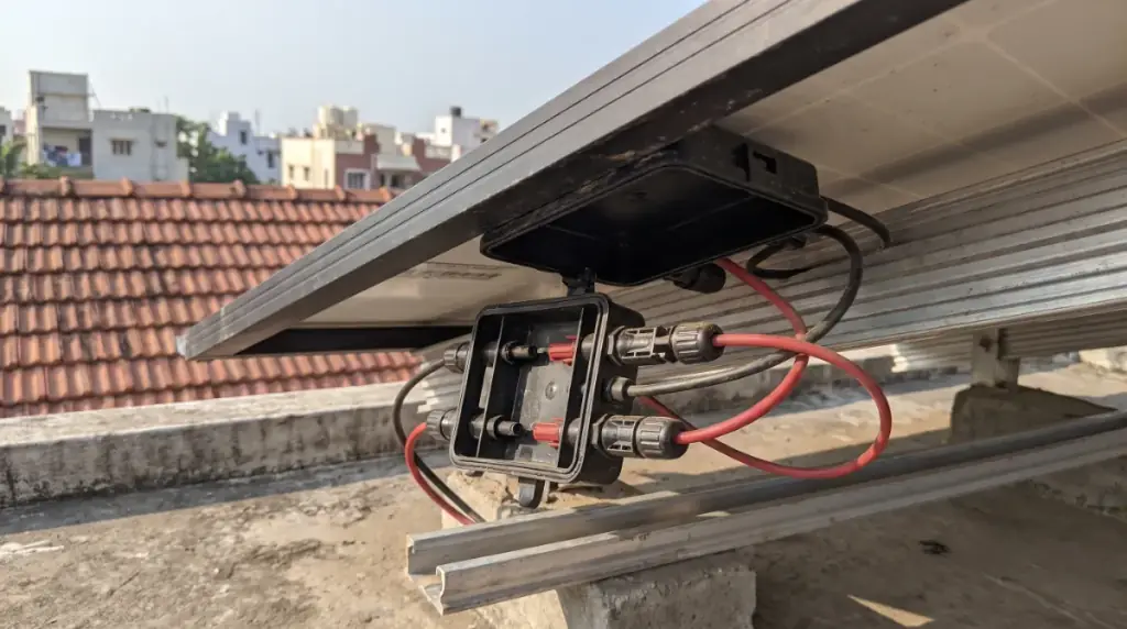 A close-up of a solar panel junction box and MC4 connectors on the underside of a module, rooftop solar in Tirupur